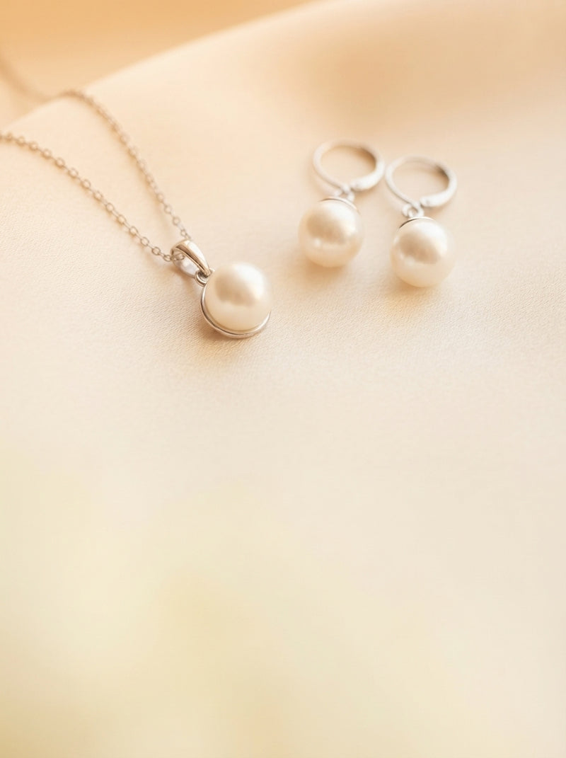 A sophisticated pearl jewelry set with a necklace and earrings displayed on a cream silk cloth in warm, natural lighting.